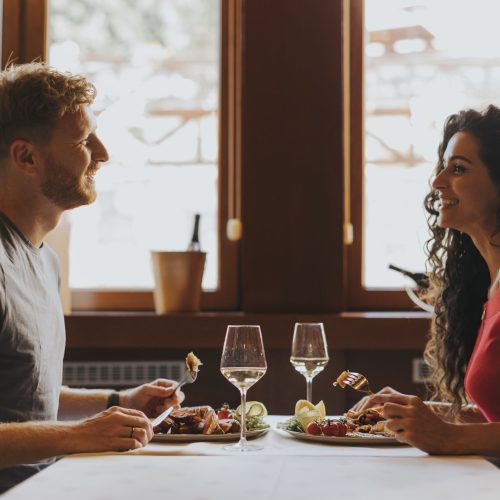 Handsome young couple having lunch with white wine in the restaurant